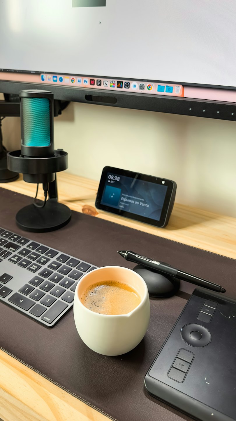 Modern computer desk setup with electronics and a coffee cup.